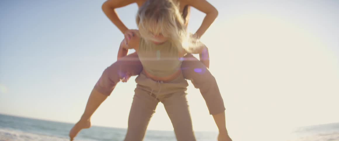 Two women dance on the beach near the sea with the bright sun shining