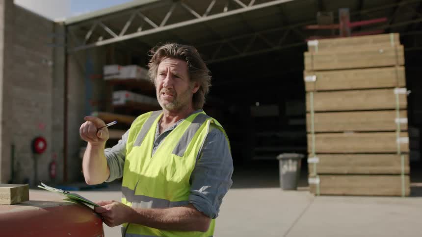 A man is taking notes in the lumber yard