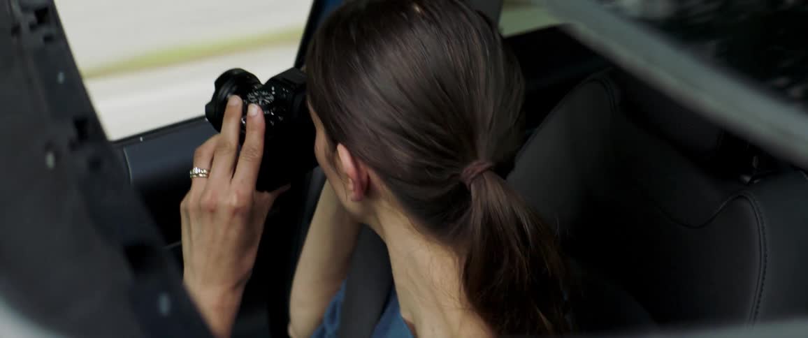 Woman riding in car takes pictures and smiles at the driver