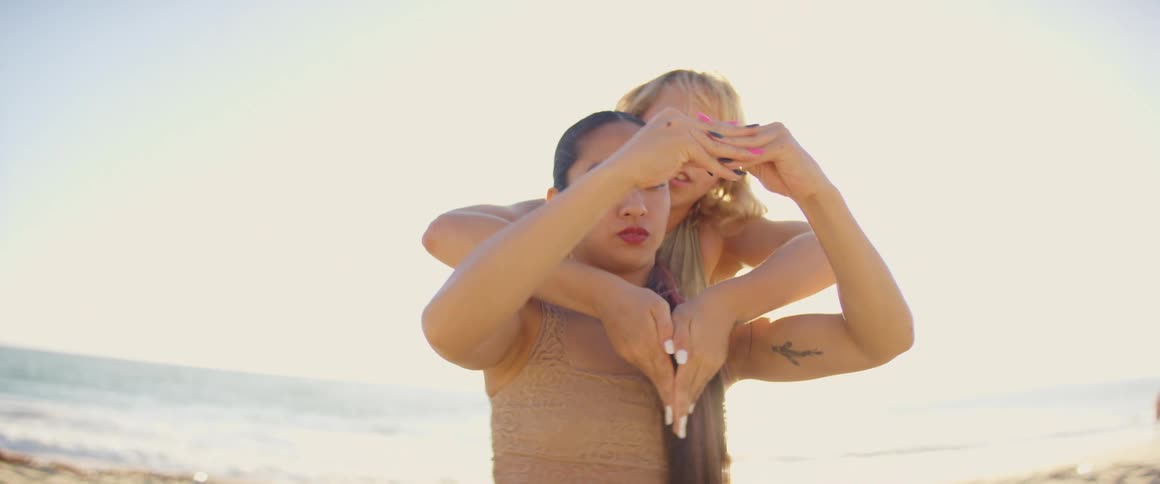 Two women gesture while dancing near the ocean at daytime