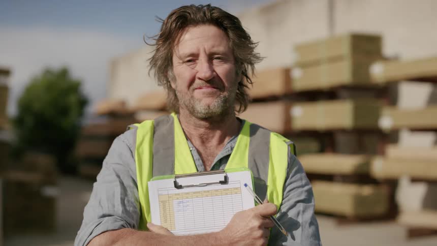 A man with arms crossed holding a clipboard