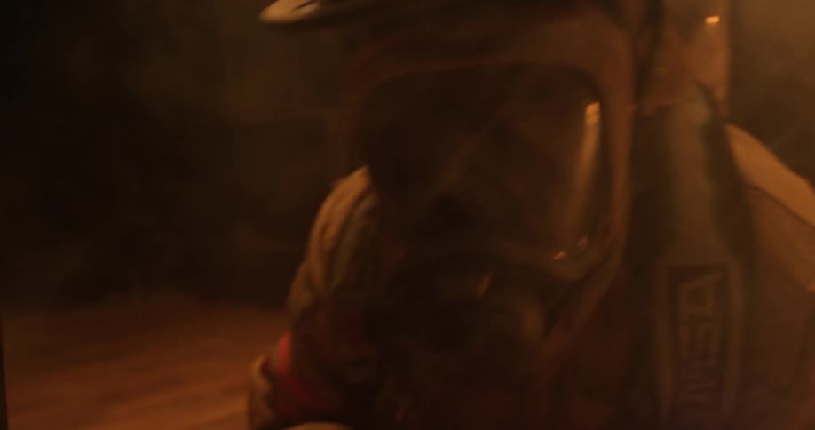 A firefighter wearing a mask crawling through a smokey room