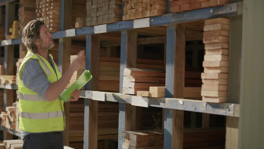 An employee wearing a vest taking stocks of wood