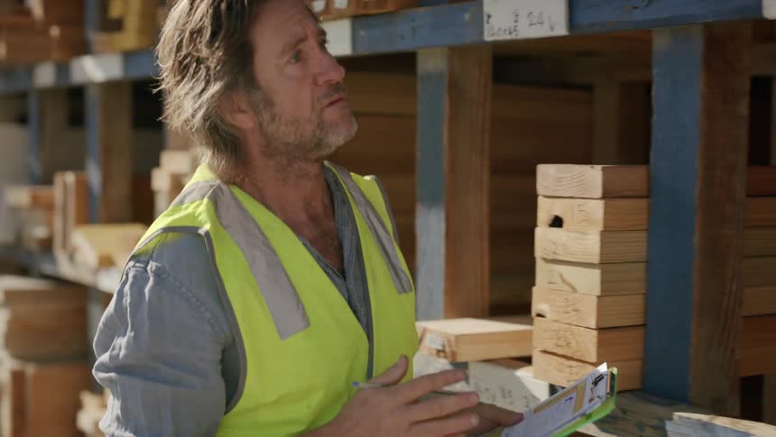 A man is taking inventory in the lumber yard