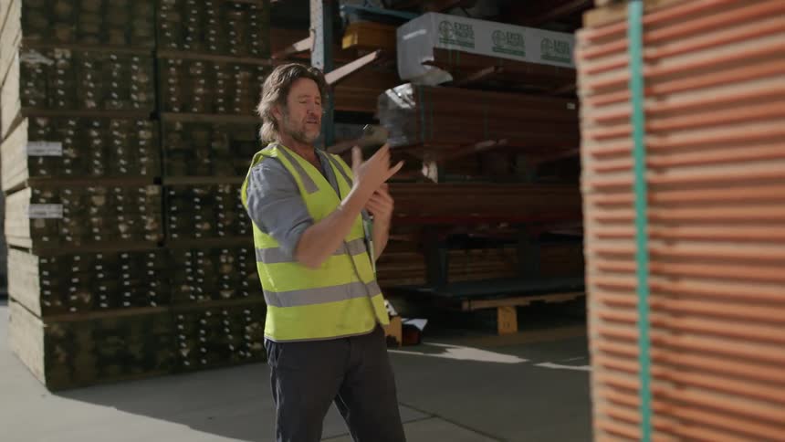 Man on green vest video calling on a mobile phone while holding a notepad