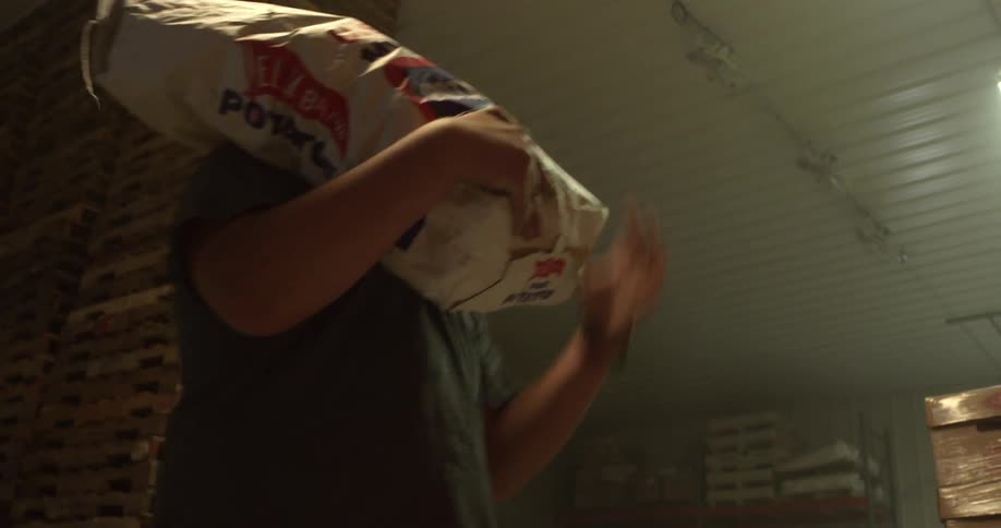 Man picks up heavy sack and hoists it over his shoulder