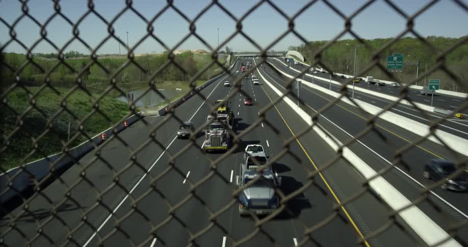 Through the fence cars travel on the road below