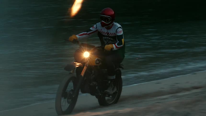 A man riding a dirt bike on the beach by the water at night