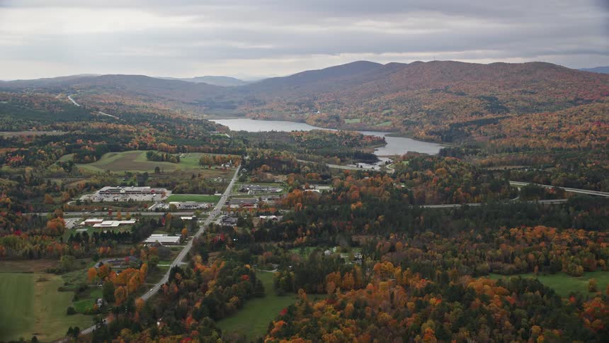 An aerial view of an urban city surrounded by green areas lakes and mountains