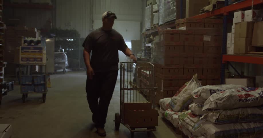 Man pushes grocery cart then lifts large potato sack