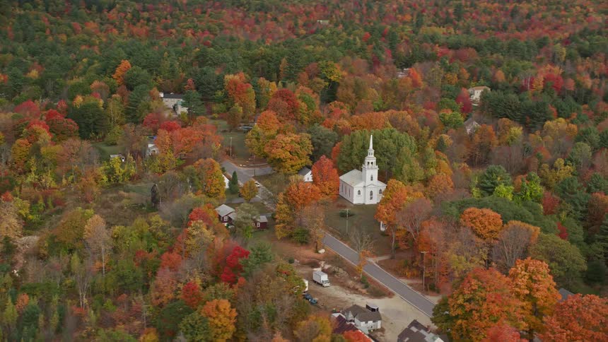 A small town with a church and other residential building surrounded by trees