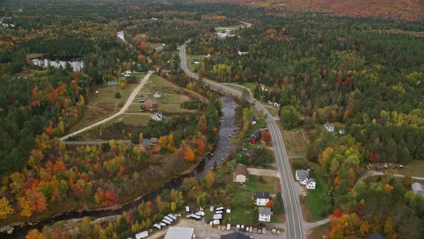 An aerial panorama of houses surrounded by nature with a central lake and trees