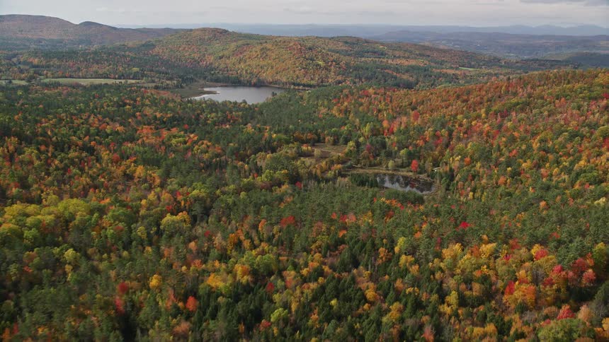 An aerial panorama of forestcovered mountains and small lake islands