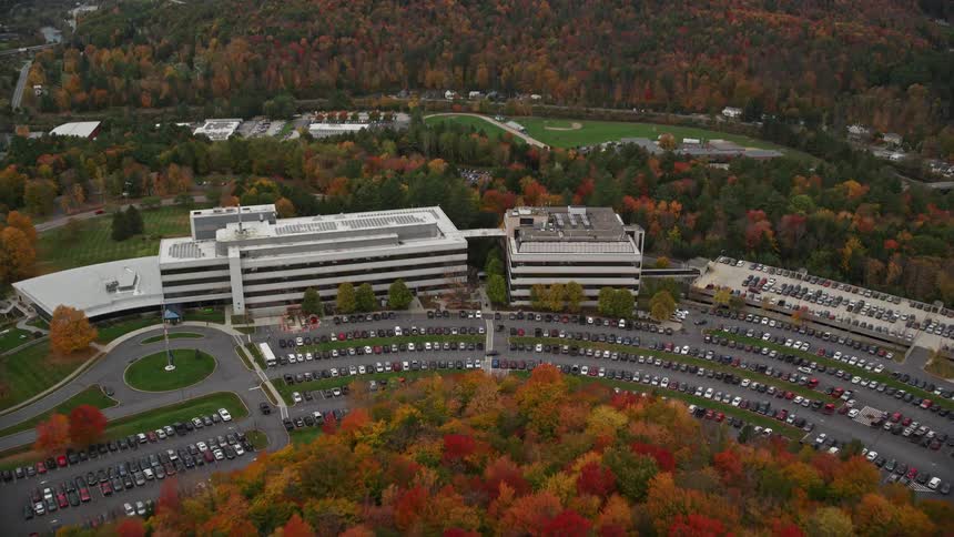 Aerial of office buildings surrounded by deciduous forest with fall foliage