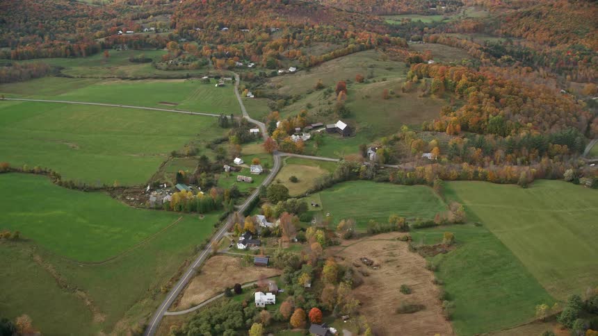 A rural region with a few houses and several fields of green grass
