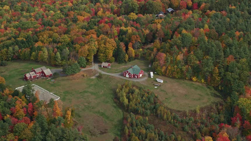 An aerial panorama of houses in fields with forests