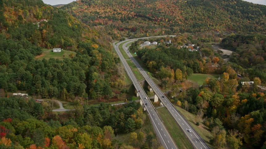 A rural region with two large roads that pass through a small village in the middle of the trees