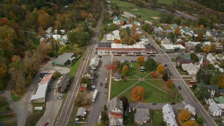 A small country town with a few houses and cars passing by on the streets