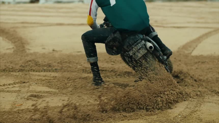 A man on a dirt bike does turns on the dirt