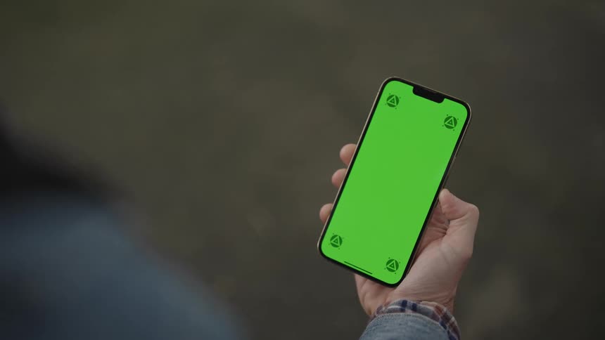 Man wearing a gray jacket holds a smartphone