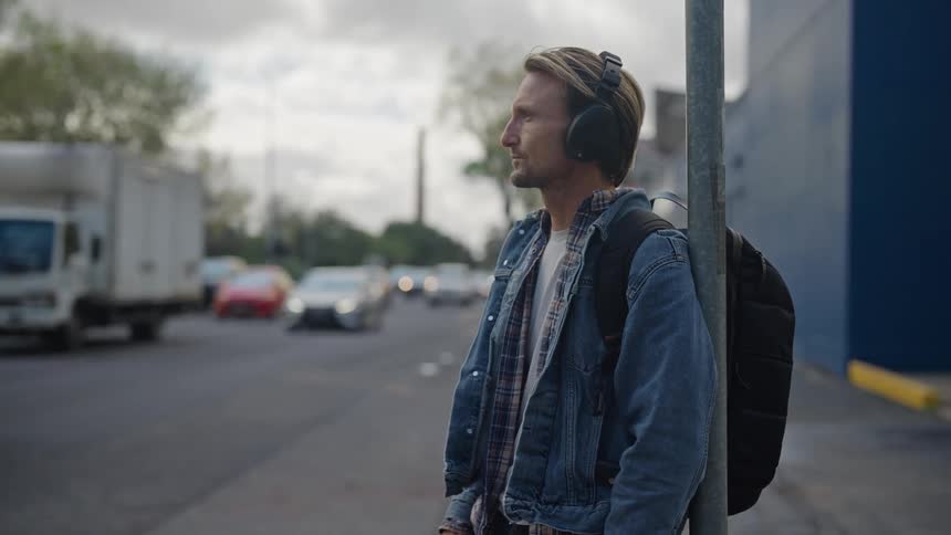 Man checks his watch while waiting at side of busy road