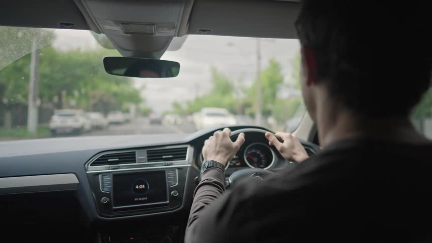 A man driving his car on a street in a quiet neighborhood