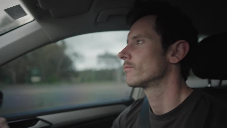 A man with his hands on the steering wheel and dancing with his head