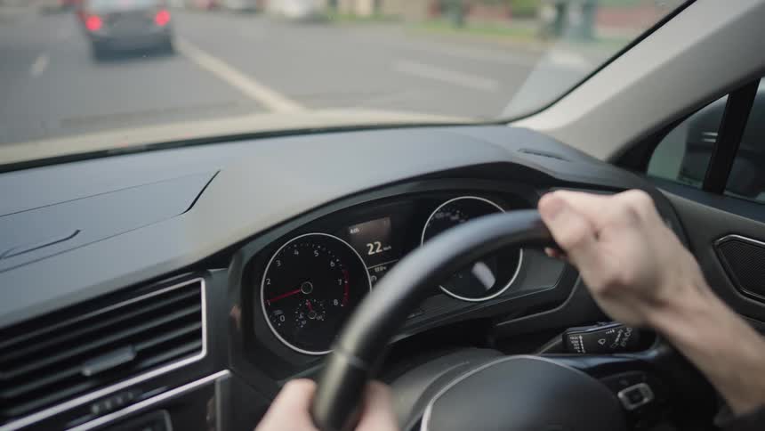 Closeup on a persons hands on the steering wheel while driving a car