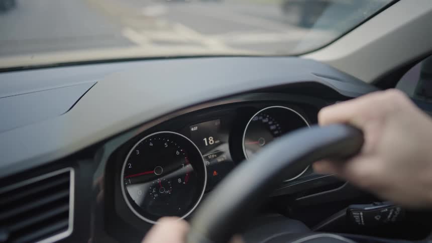 A closeup of a persons hands gripping the steering wheel to control the direction