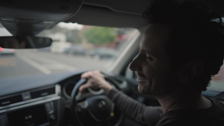 Happy man talks while driving a car in the city