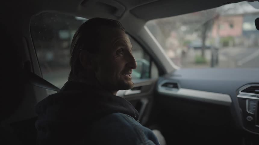 A man sitting in the front seat having a conversation inside the car