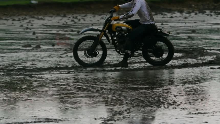 A man riding a dirt bike in the wet sand