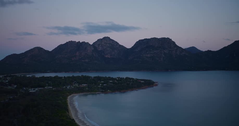 A coastal region of land facing the sea and behind huge mountains