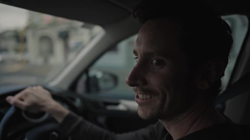 Man sitting in a car talking and laughing