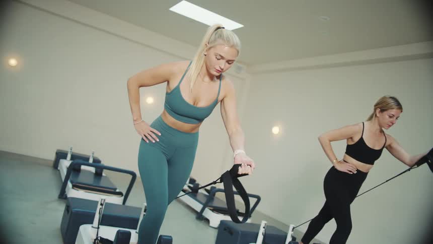 Two young women doing exercises on a gym machine