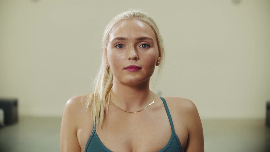 A blonde woman staring straight ahead and taking a deep breath