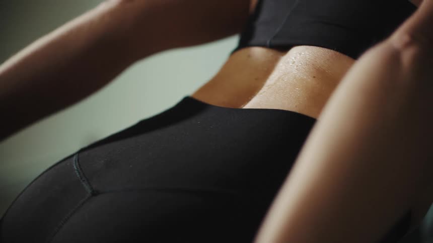Closeup of a womans back while exercising on a machine