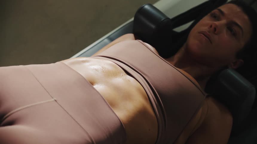 Woman doing situps on a machine with a sweaty abdomen