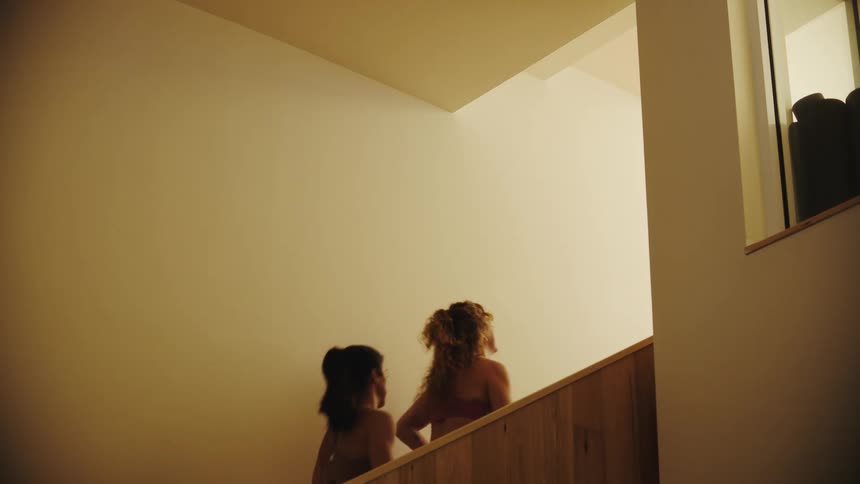 Two friends climbing a staircase in an indoor setting