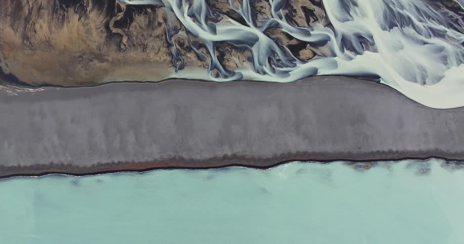 Aerial view of a river flowing down a beach near the ocean