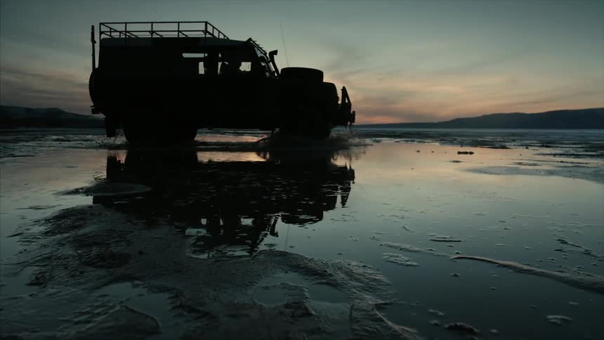 A military vehicle drives through a wet field