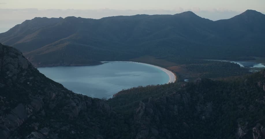 A huge mountain and just below there is a large lake with a beach