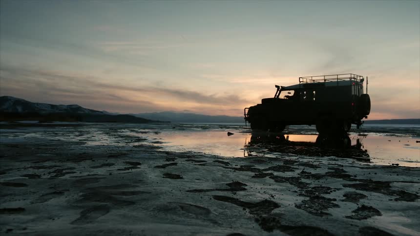 A truck drives in the water on this field as a dirt bike passes