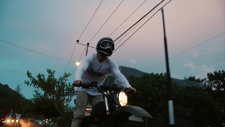 A man riding a dirt bike down a city street at night and standing