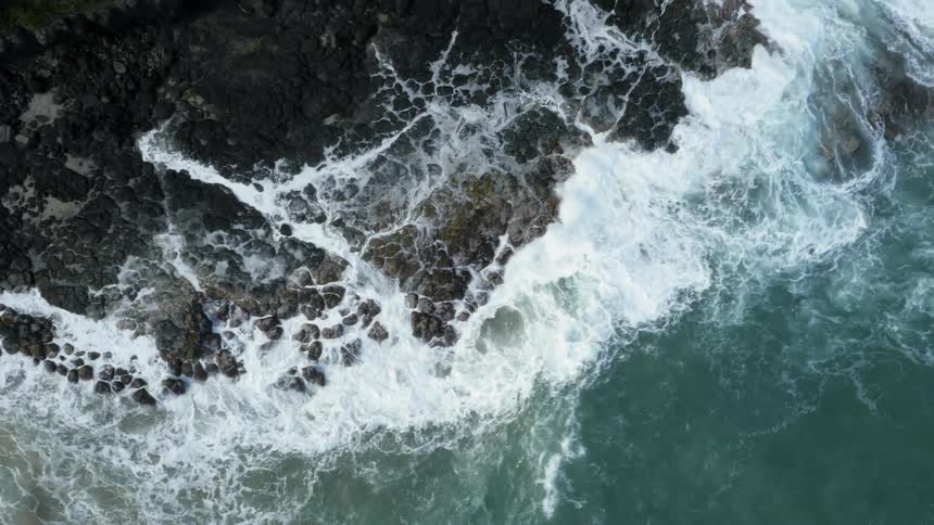 Waves crashing at the foot of a rocky mountain