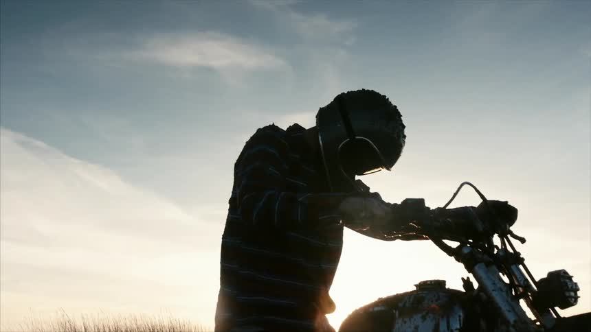 A man is sitting on a dirt bike at sunset