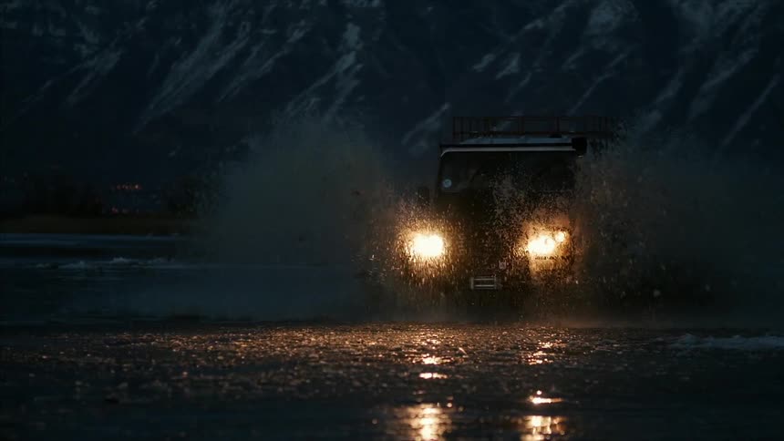 A truck is driving through the water on this field at night