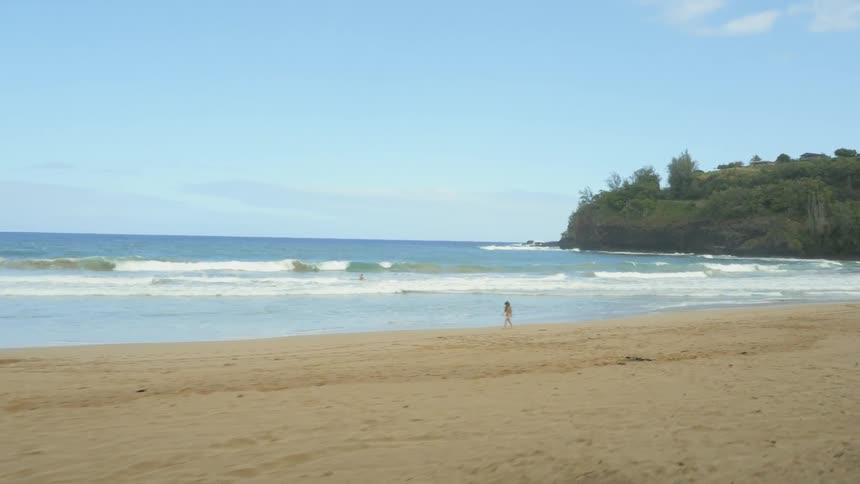 A person walking down a beach shore on a sunny day