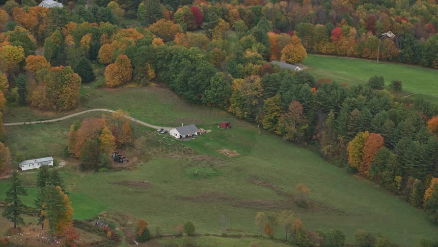 Woods in fall foliage separate rural houses
