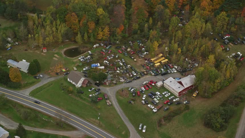 A rural area with a highway next to it and a parking lot with several cars